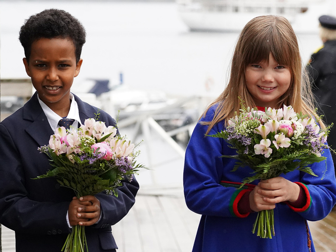 Saimon Okobalidet (8) og Mary Loise Renfjell (8) overrakte blomster til Kongen og Dronningen da de gikk i land. De ble ønsket velkommen av ordfører Ivan Haugland og politimester Heidi Kløkstad. Foto: Liv Anette Luane, Det kongelige hoff
